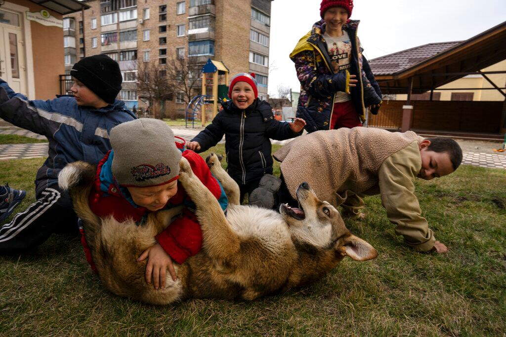 En esta imagen de archivo, niños juegan con un perro en Bucha, a las afueras de Kiev, Ucrania, el 8 de abril de 2022. Las autoridades locales contaron a The Associated Press que entre los cientos de victimas mortales habría al menos 16 niños. (AP Foto/Rodrigo Abd, archivo)