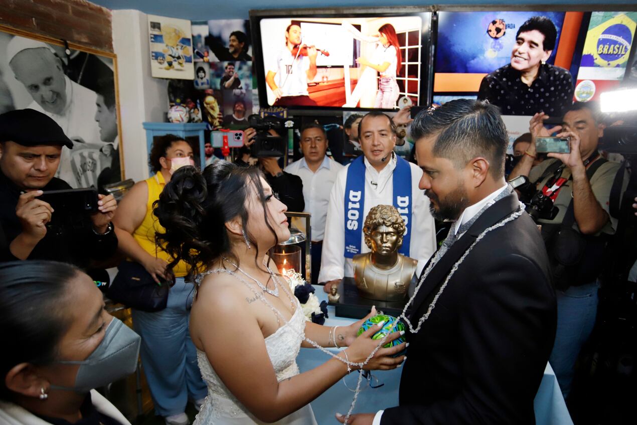 La pareja mexicana Jaziel Torres (i) y Héctor García (c) posan en una motocicleta tras su matrimonio de la Iglesia Maradoniana de México, el 1 de octubre de 2022, en el municipio de San Andrés Cholula, Puebla Foto EFE