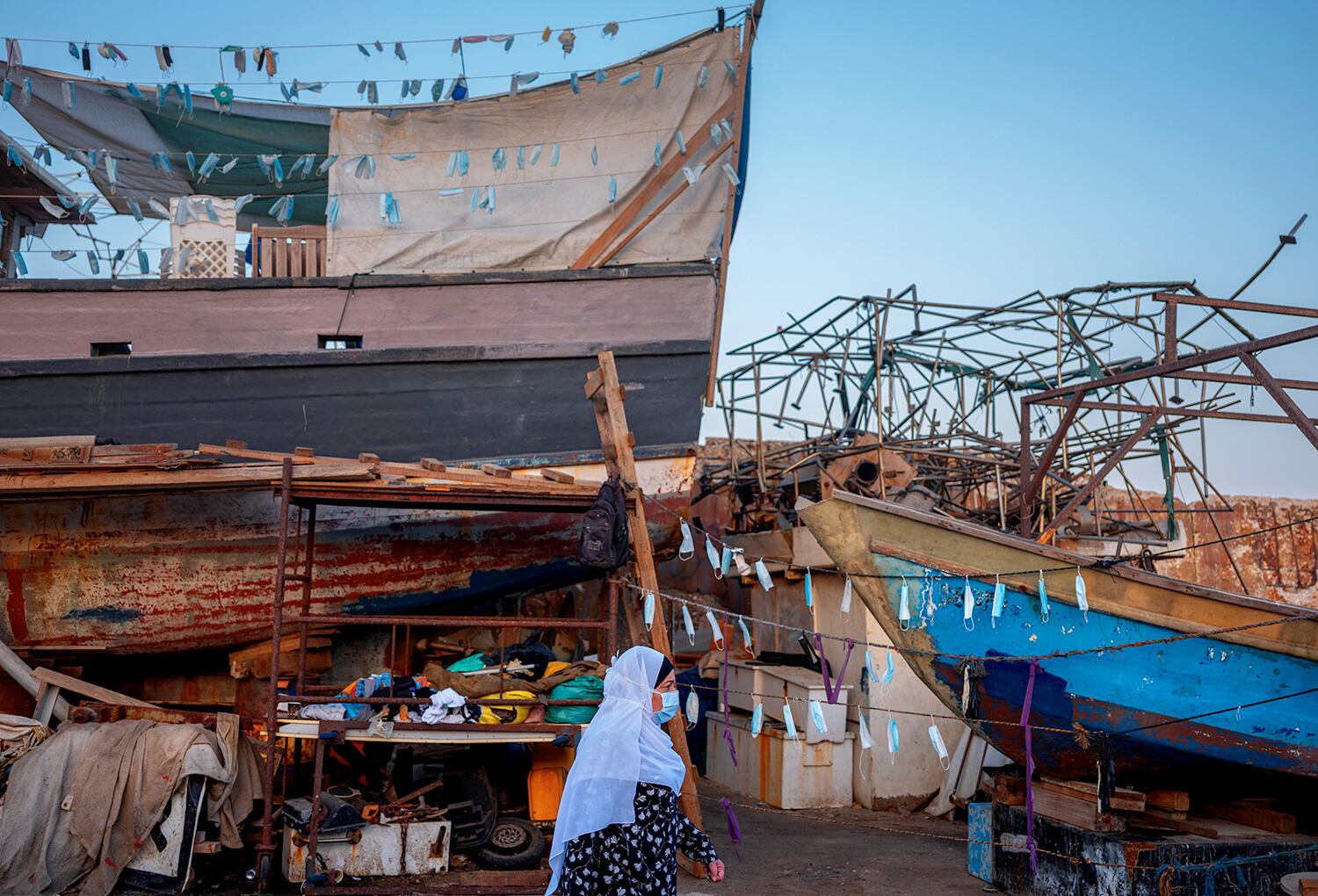 Una mujer pasa junto a barcos con mascarillas colgadas durante la cuarentena en el puerto de la ciudad de Jaffa, cerca de Tel Aviv, Israel.