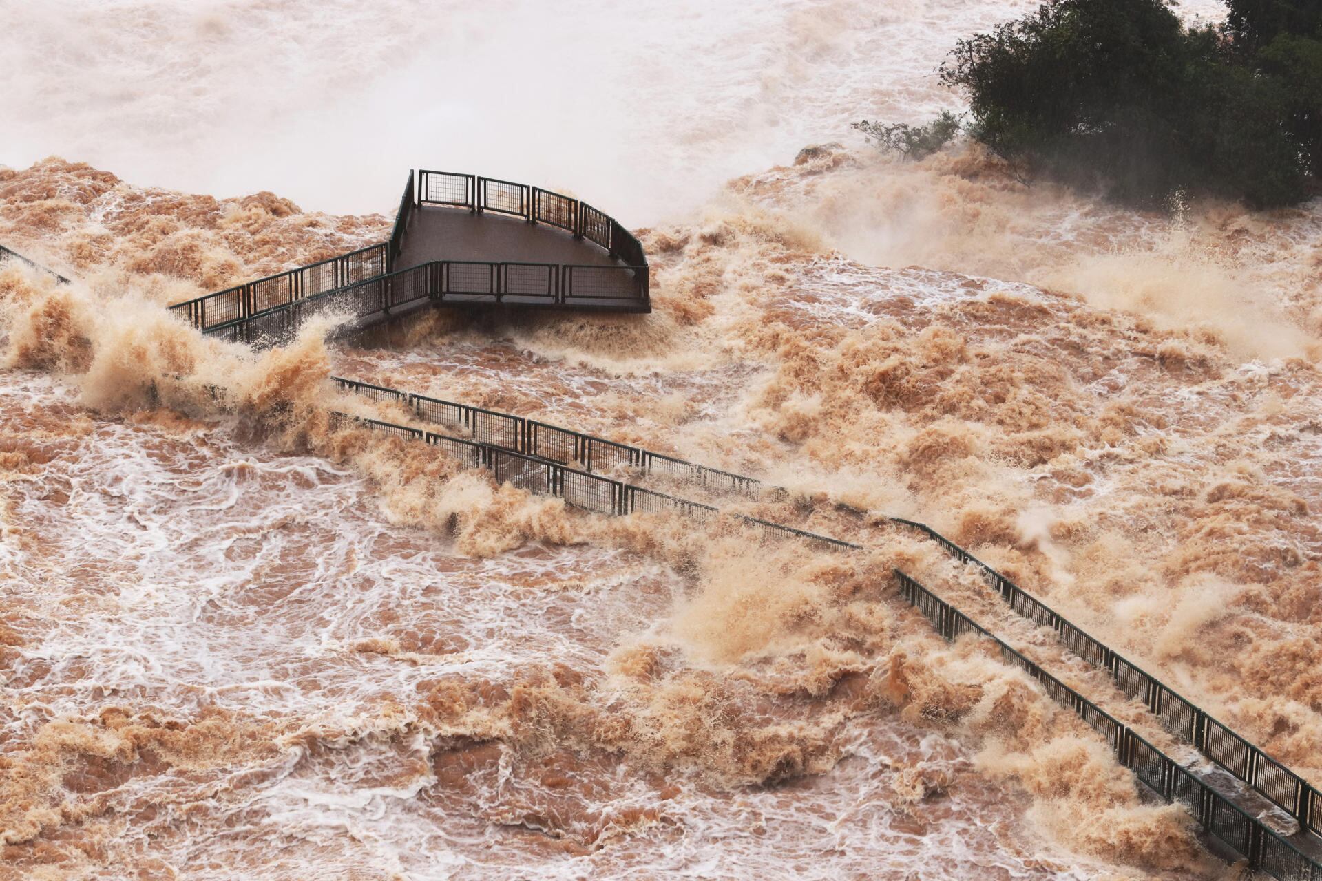 Debido a las fuertes lluvias que azotaron la región sur de Brasil, el caudal de agua en las Cataratas del Iguazú alcanzó el lunes unos 24.100 metros cúbicos por segundo. Como medida de seguridad, a la pasarela que da acceso al mirador de la Garganta do Diablo se le retiró parte de su barandilla de protección y permanece cerrada, al igual que los ascensores y pasarelas inferiores. Foto: EFE/Christian Rizzi