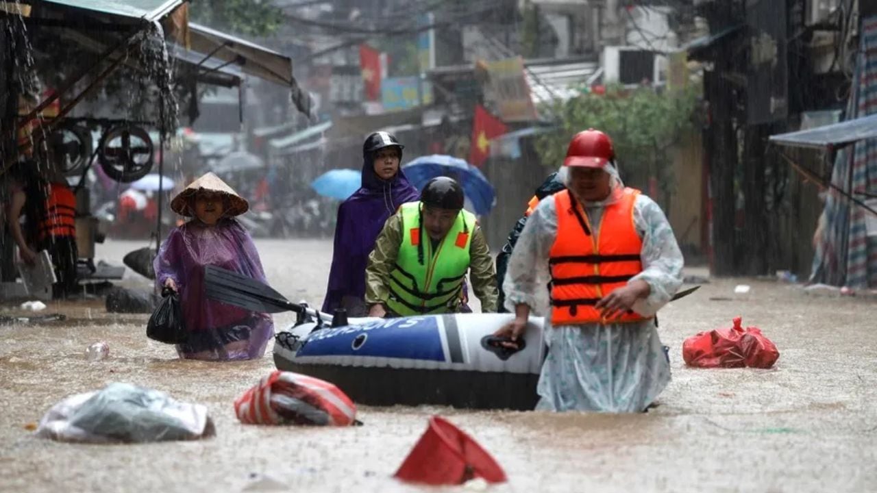 Varias personas empujan un bote inflable por una calle inundada de Hanoi, Vietnam. EFE/EPA/Luong Thai Linh