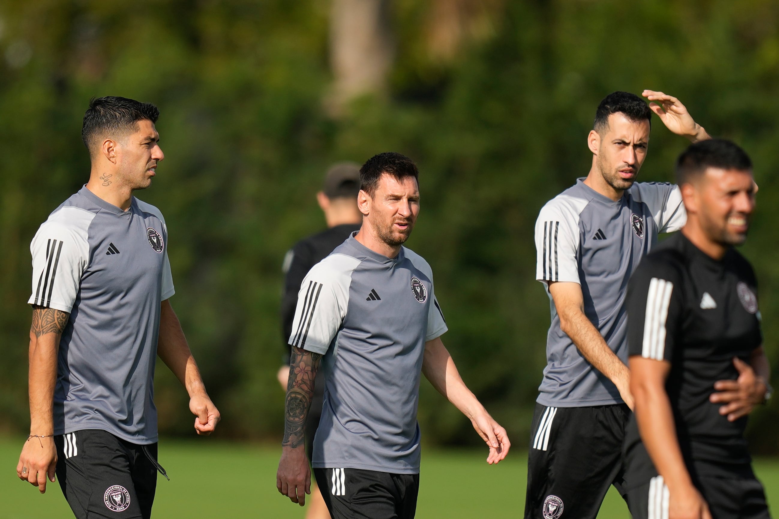 El delantero de Inter Miami Luis Suárez, a la izquierda, camina con el delantero Lionel Messi, centro, y el defensa Sergio Busquets, segundo a la derecha, durante una sesión de entrenamiento de fútbol de la MLS, el sábado 13 de enero de 2024, en Fort Lauderdale, Florida (AP Foto/Rebecca Blackwell)