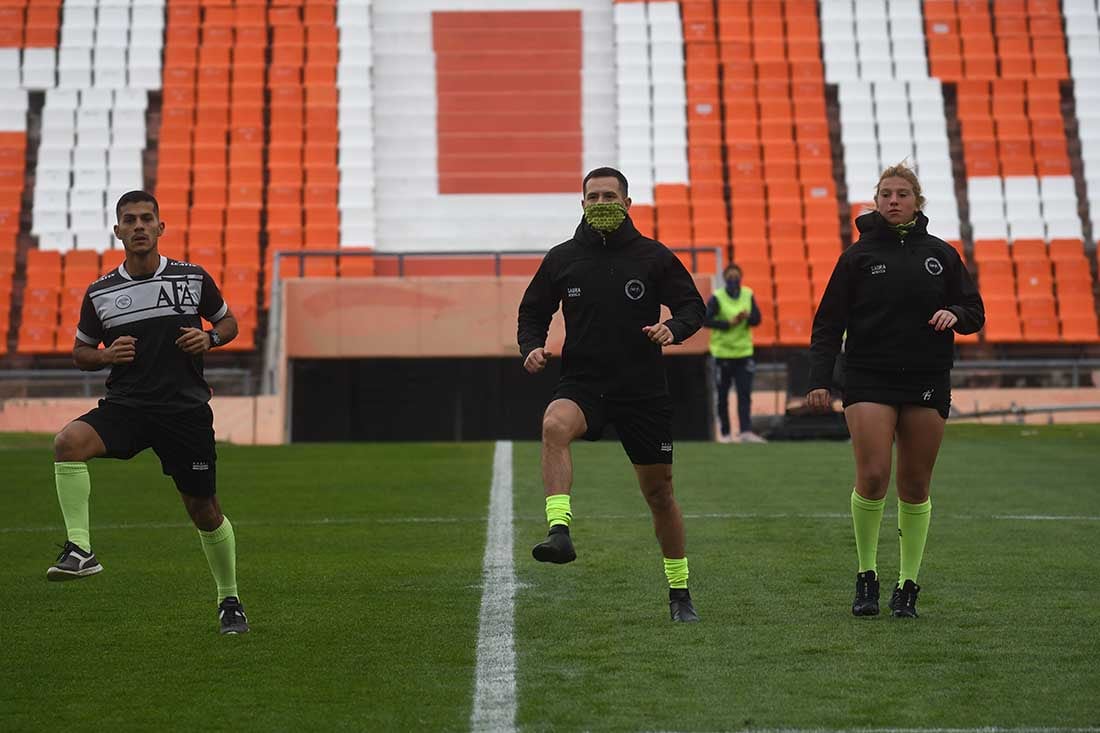 La terna arbitral realiza el calentamiento físico antes de comenzar el partido en una mañana muy fría.