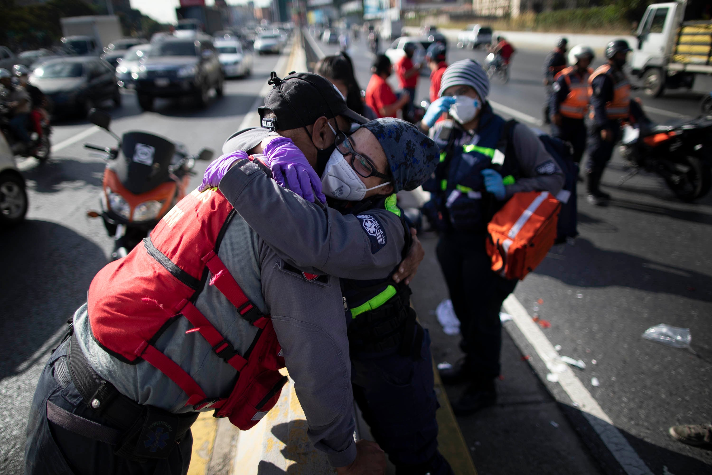 La socorrista voluntaria Zully Rodiz (der) abraza a un socorrista de los servicios públicos en el lugar de un accidente de tráfico en Caracas.