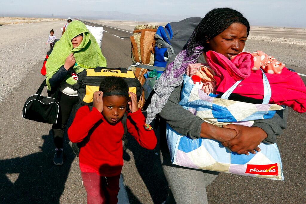 Migrantes venezolanos caminan por una carretera tras ingresar a Chile por la frontera con Bolivia, cerca de Colchane, Chile