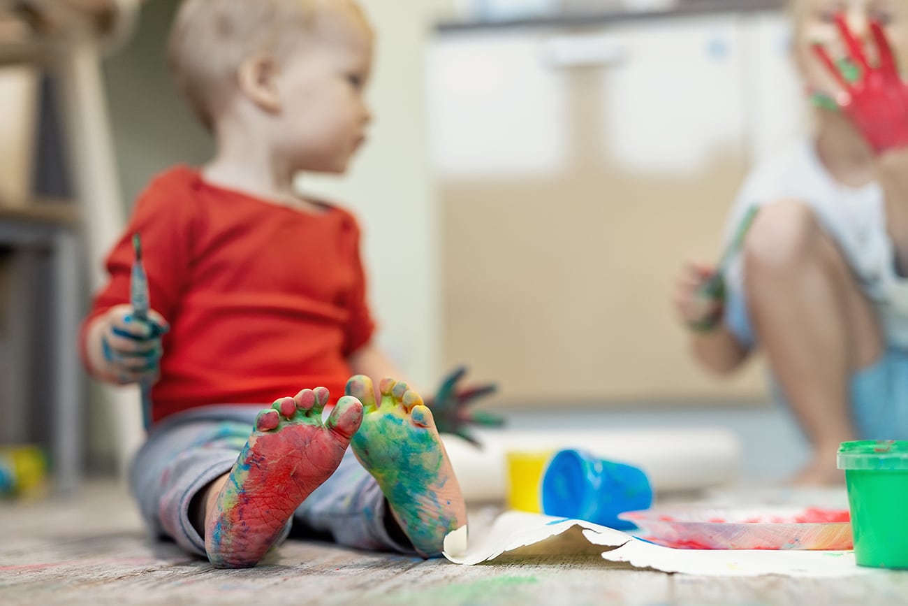 Niños disfrutan divirtiéndose pintando con pincel y acrílicos en casa.