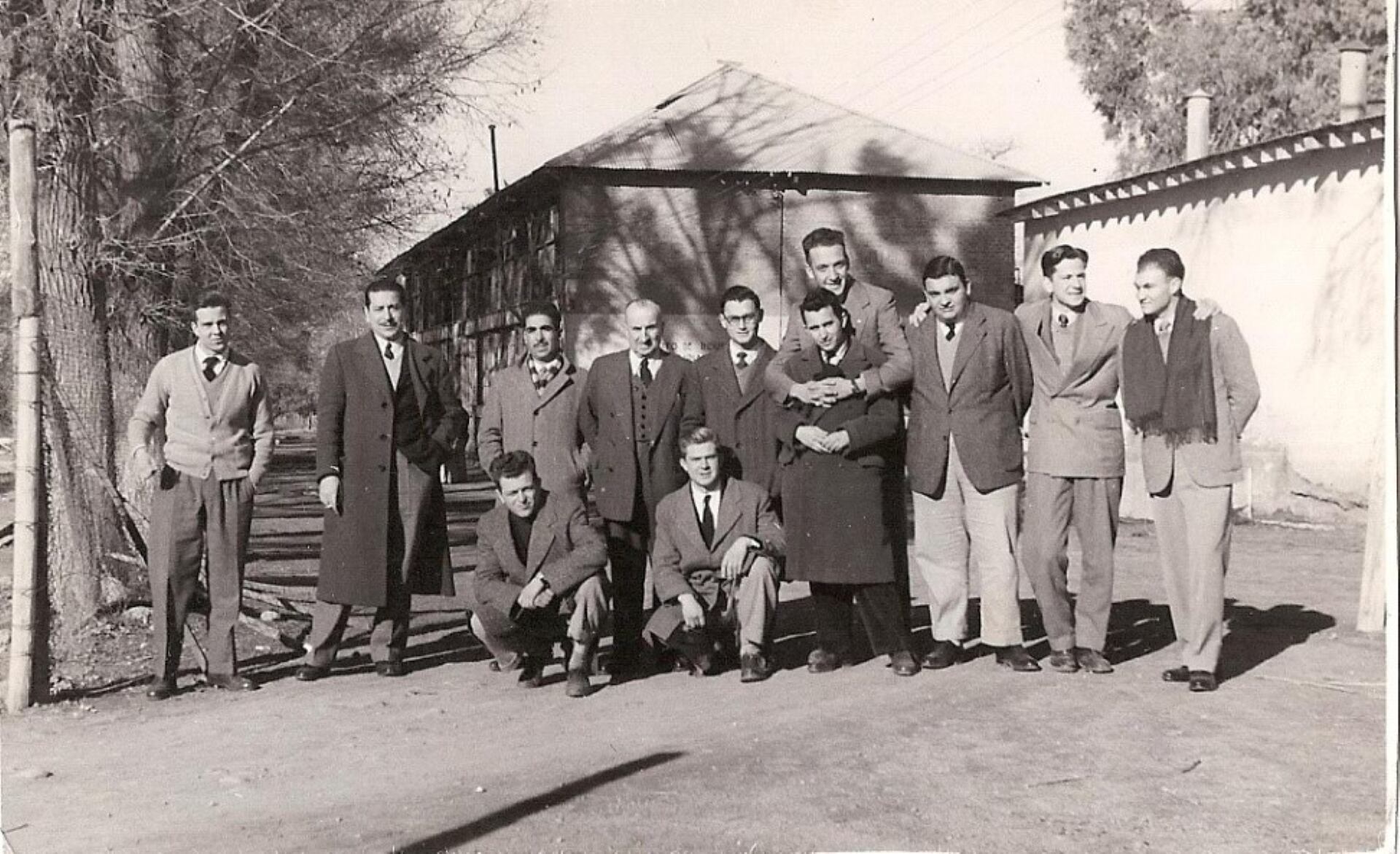 FACULTAD de CIENCIAS AGRARIAS en la Quinta Agronómica, 1954: alumnos de 2do año, de izquierda a derecha:
Parados: Luis Merlo, prof. Aquiles Piedrabuena (Cálculo Estadístico), Moisés Nazrala, Ing. Antonio Poy Costa (Mecánica Agrícola), Jorge Chambuleyron, Manuel García (abrazando), Nello Cucci, Bartolomé Del Bono (no terminó la carrera), Jorge Romero Gei y Hugo Martínez. Sentados: Jorge Tacchini (*) y Roberto Pozzoli. El edificio de atrás es la fábrica de aceite de oliva y el Instituto de Industrias Agrarias. En planta alta funcionaban las cátedras de Zoología Agrícola y Fruticultura. En el edificio lateral derecho aledaño al zanjón Frías (atrás de Martinez) funcionaba la industria conservera y de lácteos. Foto: Gentileza