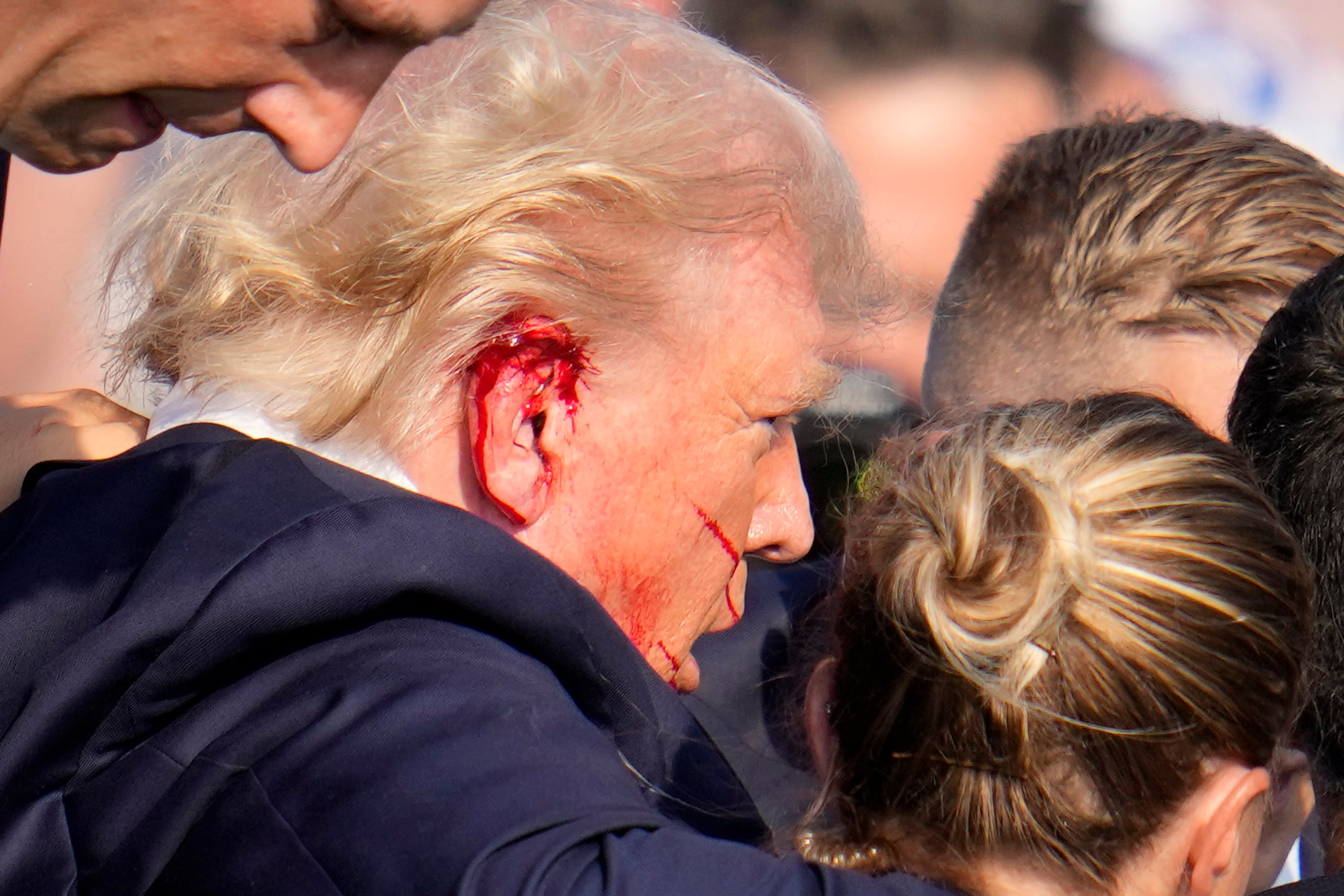 El expresidente estadounidense Donald Trump es escoltado por agentes del Servicio Secreto tras el aparente intento de asesinato en un evento de campaña en Butler, Pensilvania, el 13 de julio del 2024. (Foto AP/Gene J. Puskar)