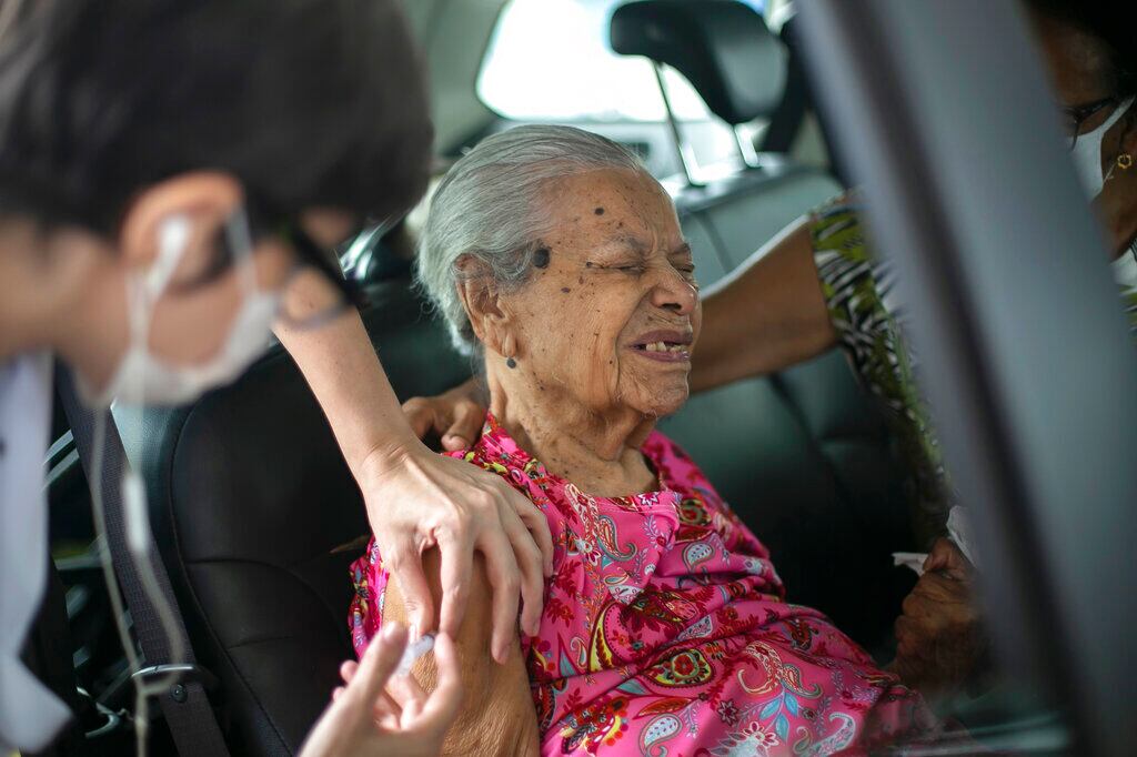 Maria de Lourdes, de 101 años, hace una mueca al recibir una dosis de la vacuna contra el coronavirus de la farmacéutica china Sinovac Biotech, en un puesto de vacunación desde el auto habilitado en el Sambódromo, en Río de Janeiro