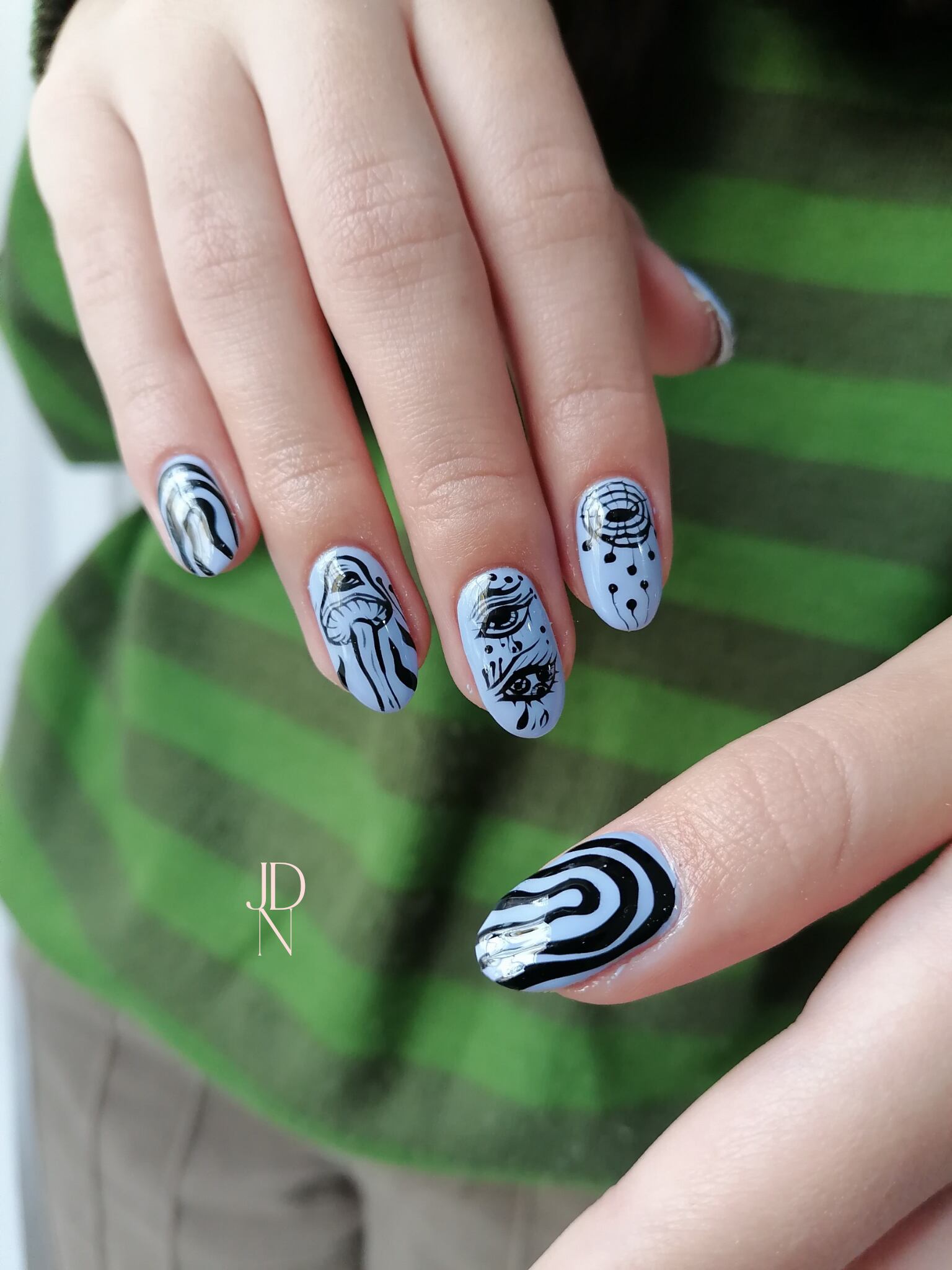 Uñas celestes con diseños en negro. 