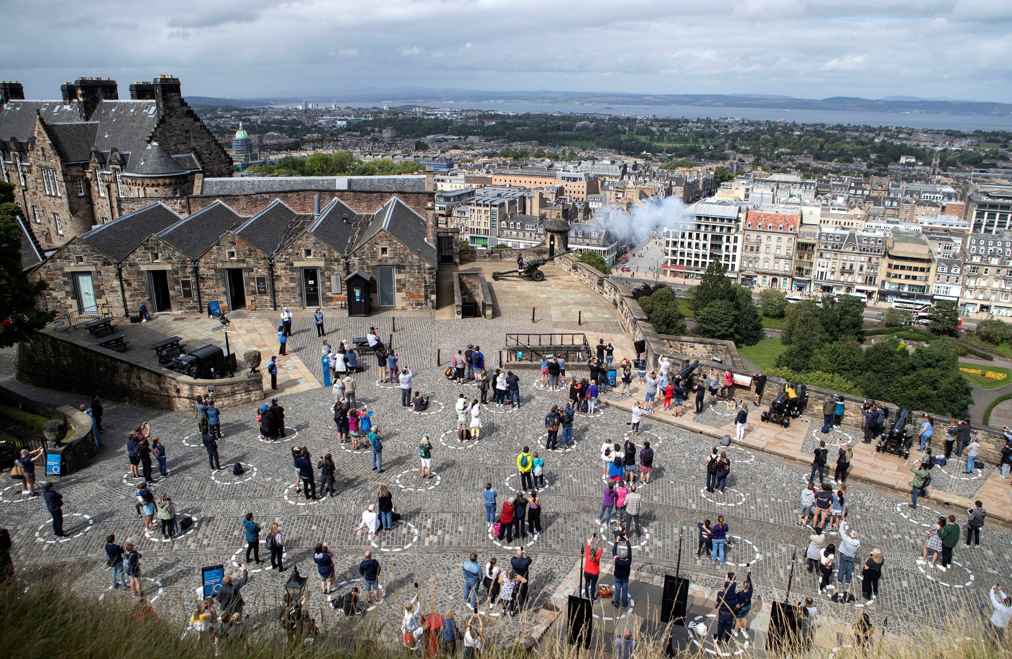 Los visitantes en el Castillo de Edimburgo se encuentran socialmente distanciados en círculos marcados, Escocia. AP