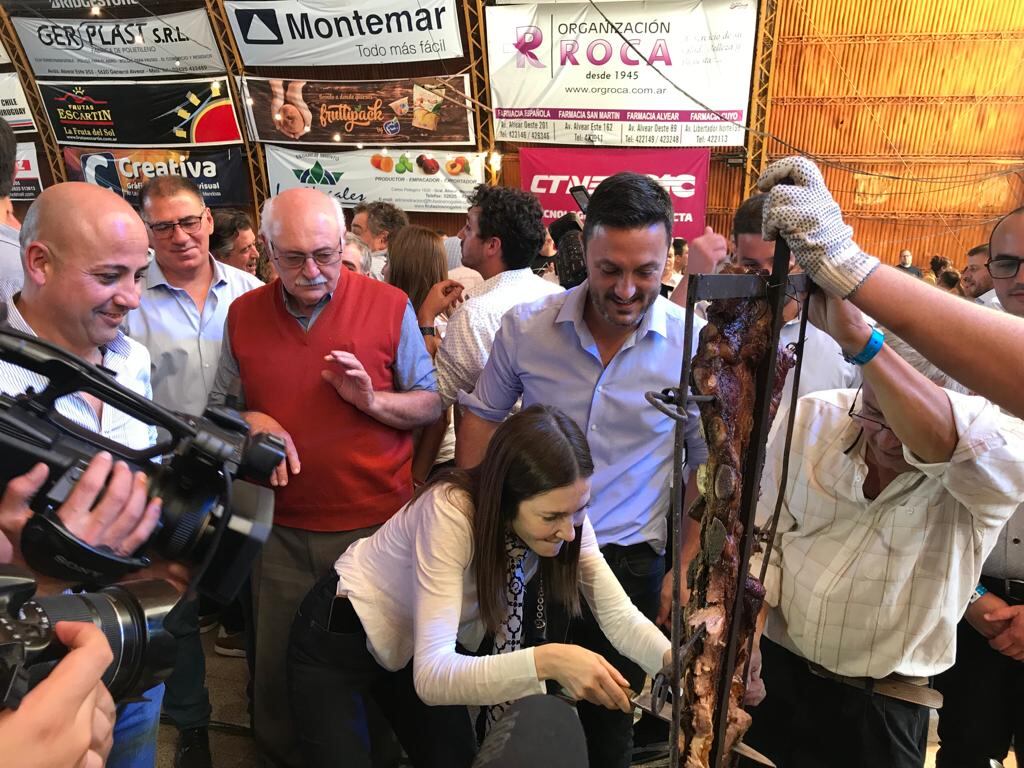 Cristina Pérez corta las costillas, ante la atenta mirada de Luis Petri en la Fiesta de la Ganadería en General Alvear.