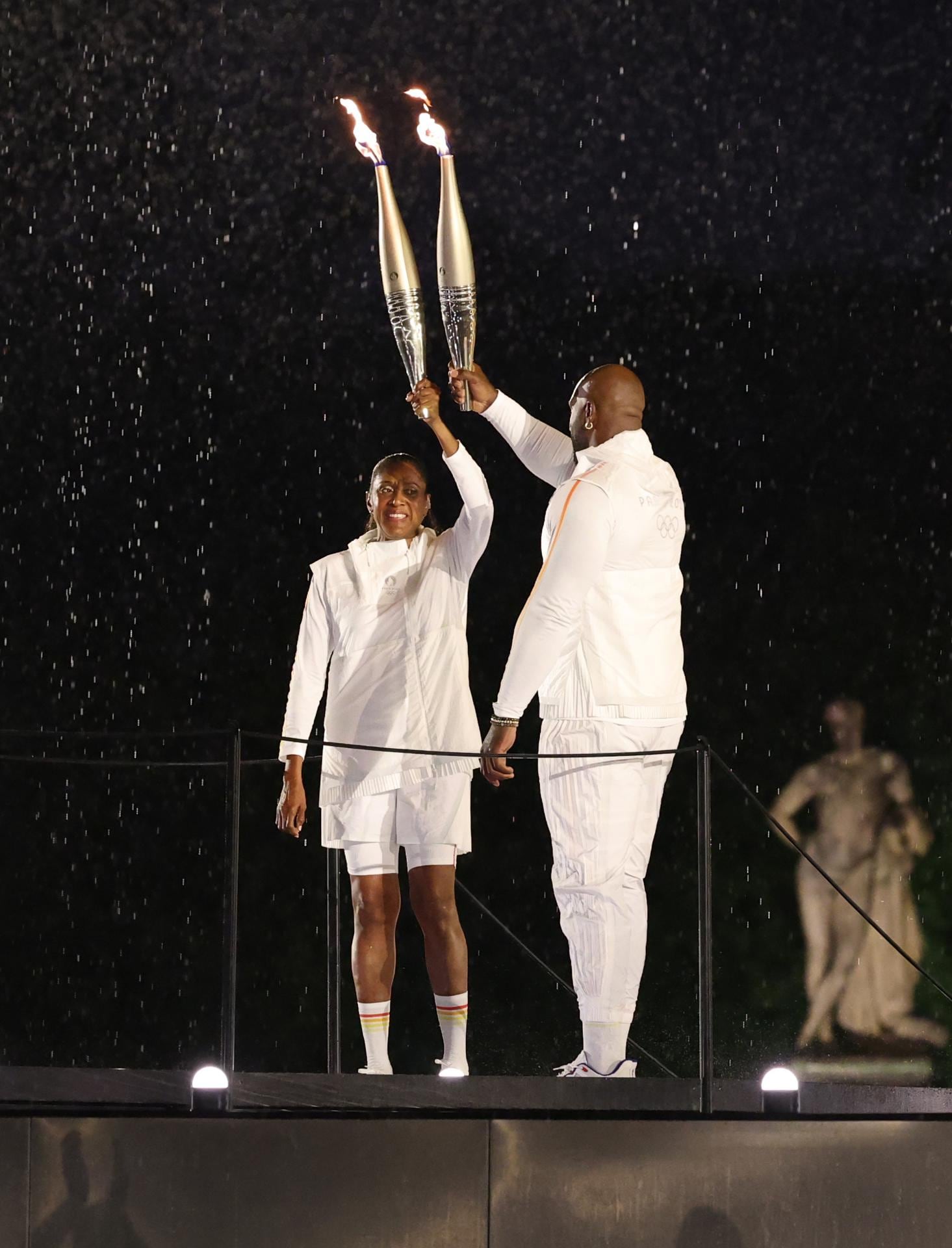 Los portadores de la antorcha Marie-Jose Perec (i) y Teddy Riner (d) llegan para encender el pebetero durante la ceremonia de apertura de los Juegos Olímpicos de París 2024, en París, Francia. Foto: EFE/EPA/Jan Woitas / POOL