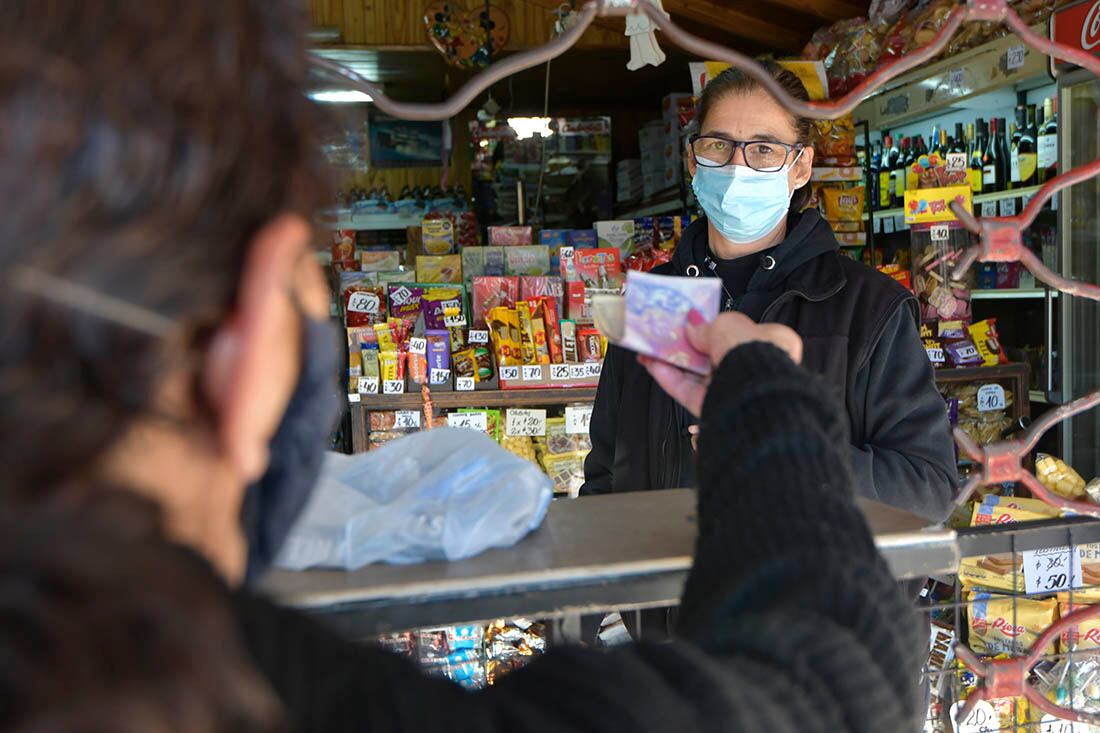 Un almacén atiende tras la reja durante el primer día hábil de la cuarentena.