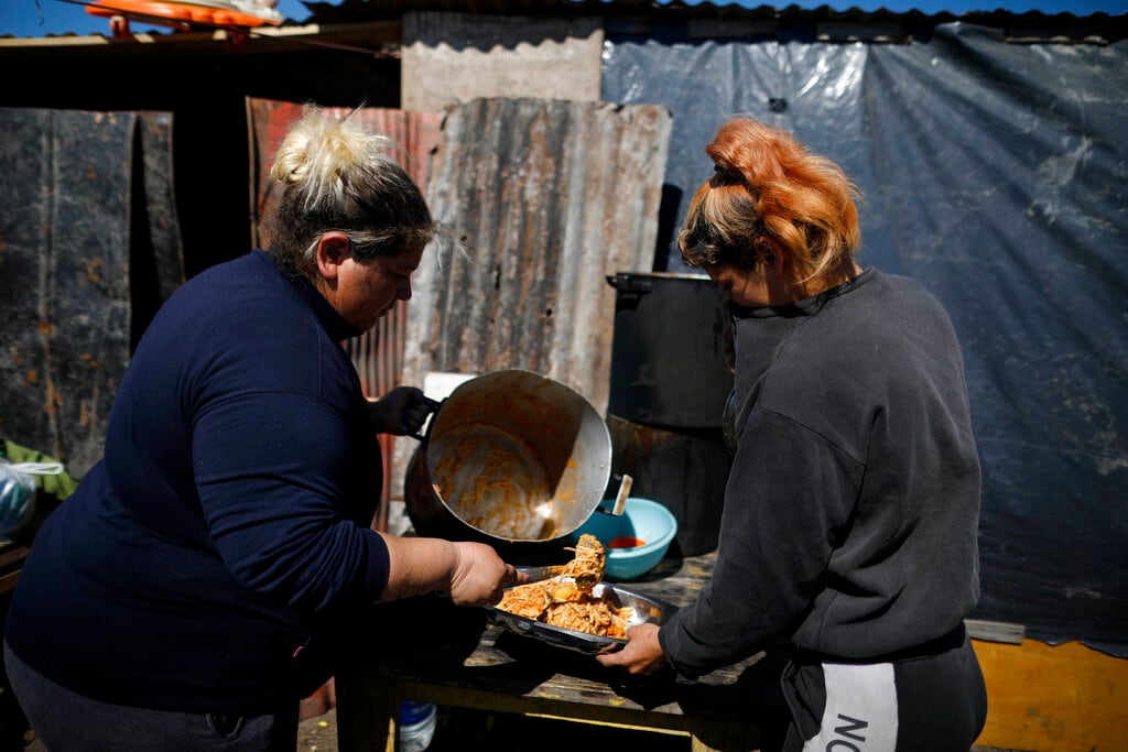 Giselle Espinosa sirve la última ración de comida en un comedor de beneficencia en un campamento de ocupantes ilegales en Guernica, provincia de Buenos Aires, Argentina,