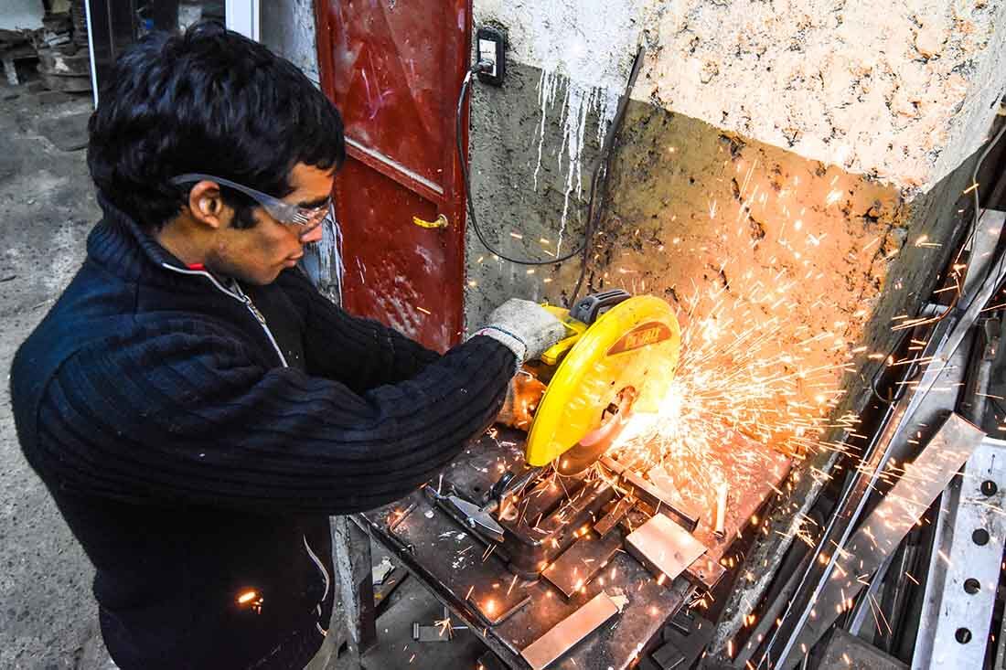 Sebastián Carrera en su taller metalúrgico, trabaja en su máquina circular cortando unos caños