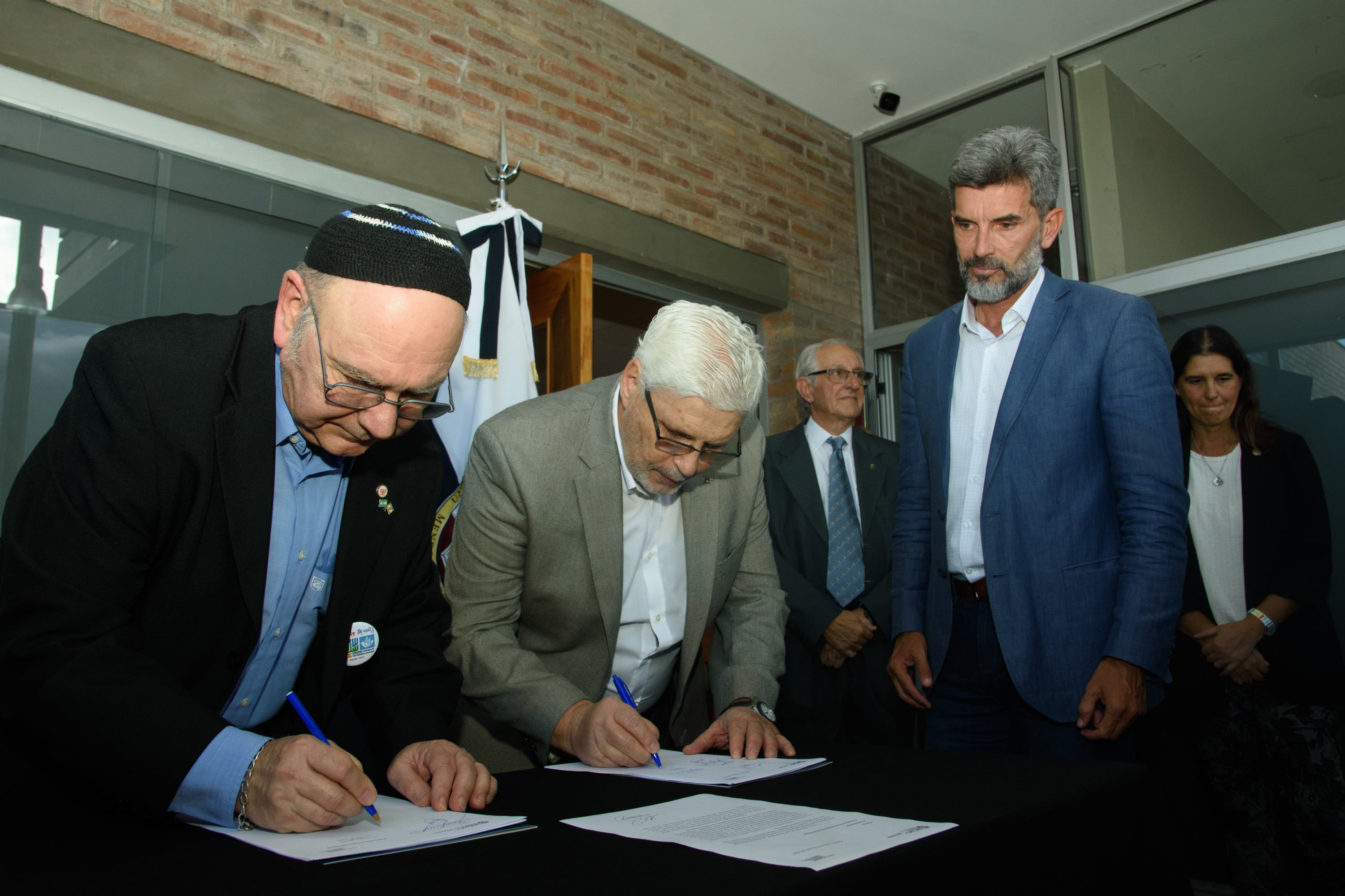 El intendente Ulpiano Suarez, espera su turno, mientras plasman su firma Jorge Mazzitelli, de la Sociedad Israelita de Mendoza, y el rector José Balacco. Foto: UNCUYO