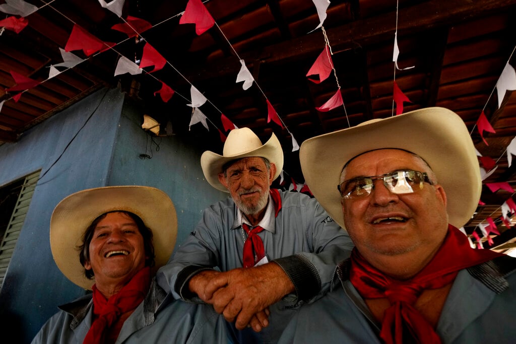 Unas personas sonríen mientras participan en los eventos por la tradición religiosa de la "Fiesta del Divino Espíritu Santo", en la región rural de Pirenópolis, en el estado de Goias, Brasil, el sábado 28 de mayo de 2022. (AP Foto/Eraldo Peres)