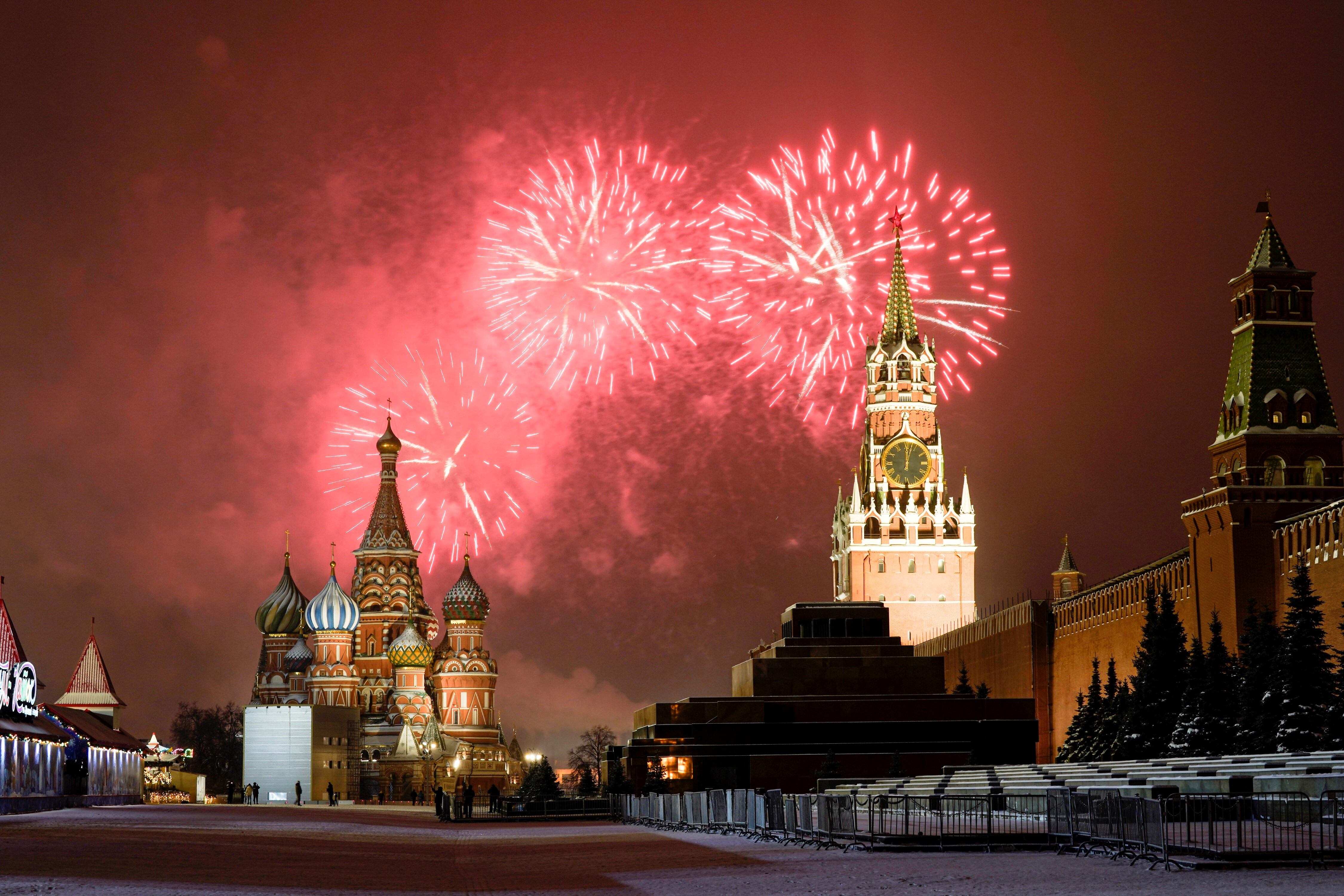 Fuegos artificiales explotan sobre la Catedral de San Basilio y el Kremlin con la Torre Spasskaya se ven en la Plaza Roja vacía debido a las restricciones pandémicas durante las celebraciones de Año Nuevo, en Moscú