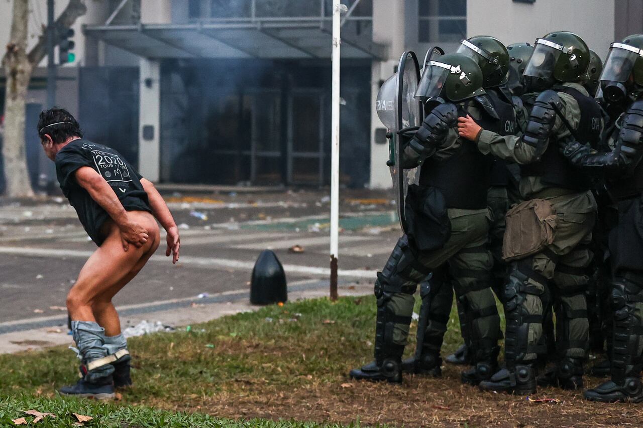 Un hombre se desnuda frente a la policía durante enfrentamientos entre la policía y personas que protestan a las afueras del senado. Foto: EFE/ Juan Ignacio Roncoroni