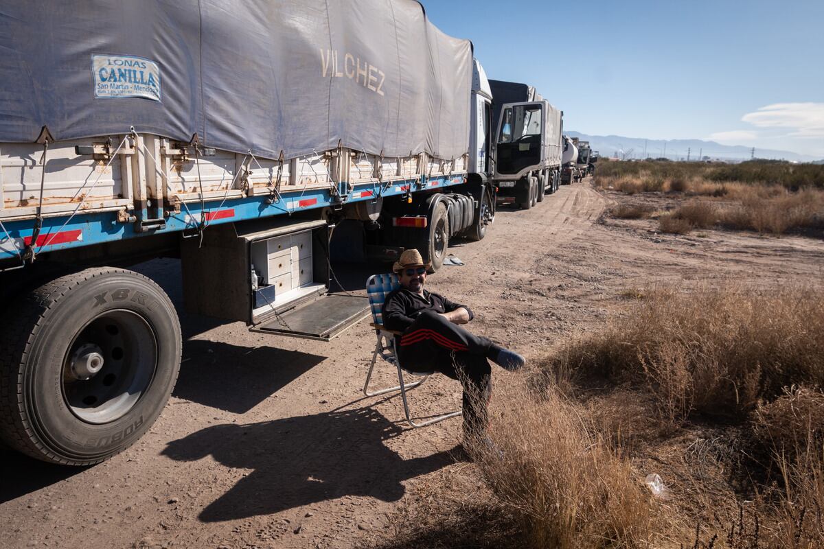 Un camionero espera sentado al lado de su camión en la larga fila de vehículos para cargar gasoil. Foto: Ignacio Blanco / Los Andes 