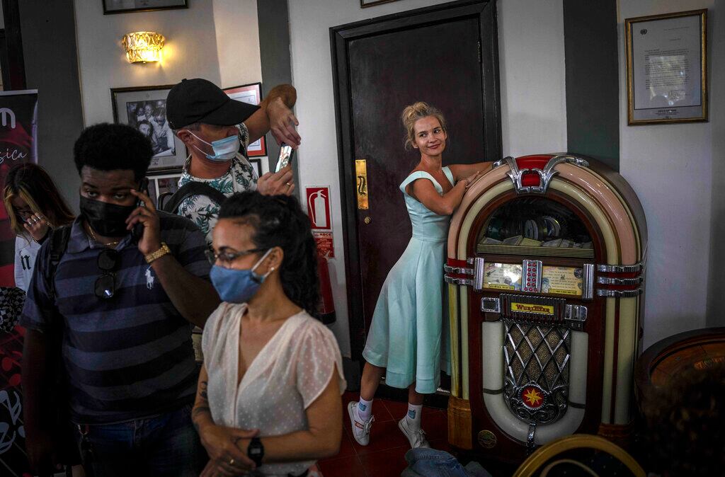 Una turista posa para una foto junto a una gramola Wurlitzer mientras reporteros asisten a una conferencia de prensa en el Hotel Nacional, en La Habana, Cuba, el 9 de febrero de 2022. (AP Foto/Ramón Espinosa)