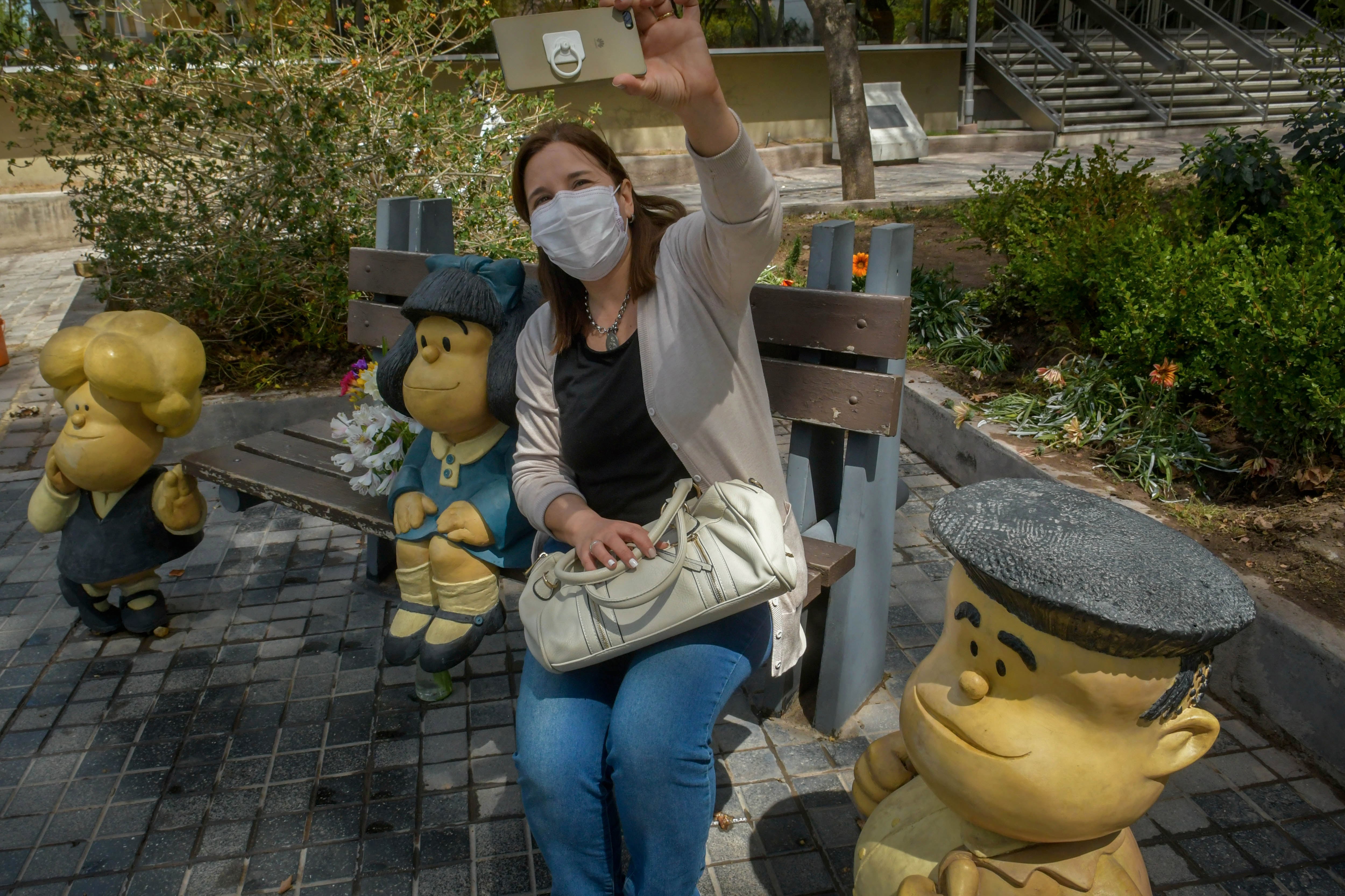 Una mujer se saca una selfie con las esculturas de los personajes creados por Quino en la ciudad de Mendoza.