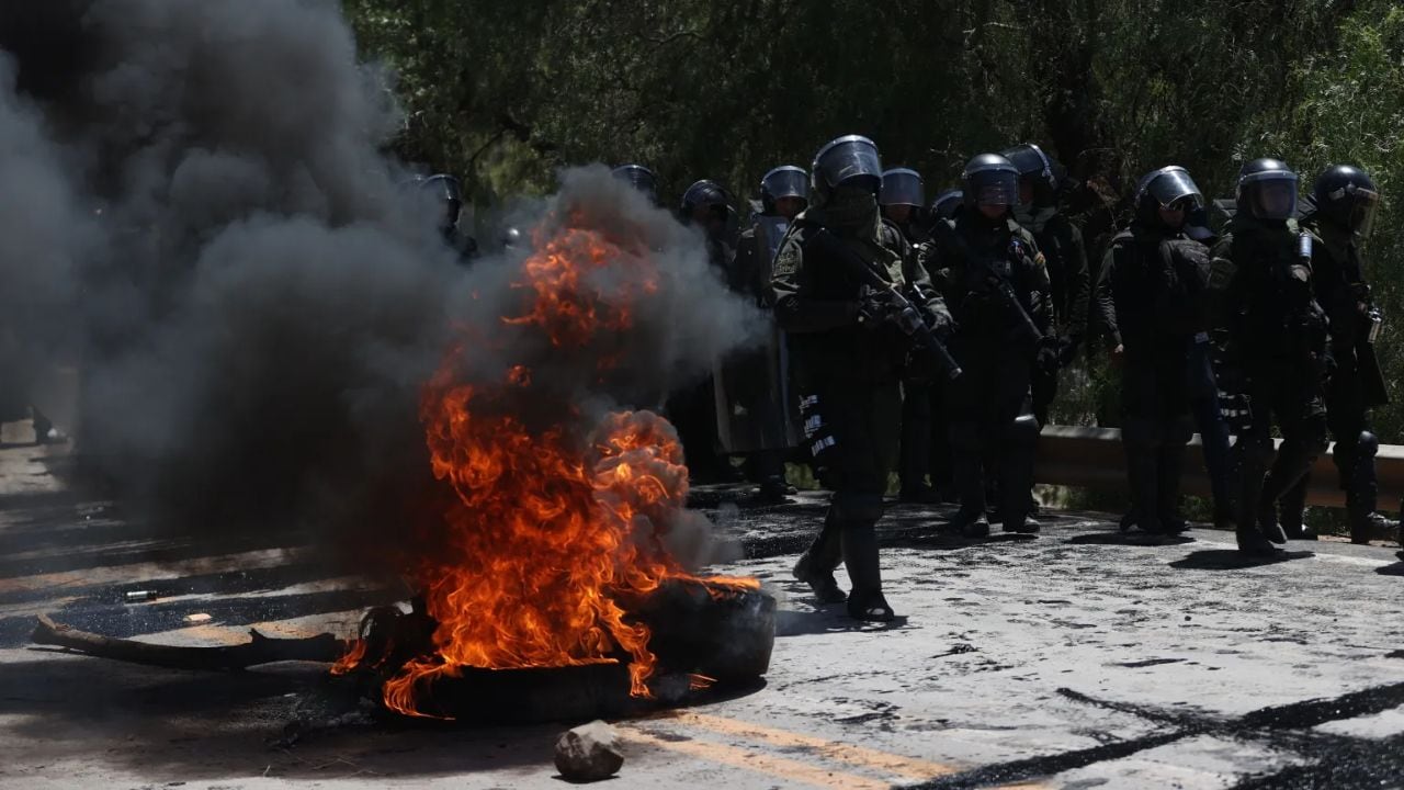 Integrantes de la Policía Boliviana caminan por una vía bloqueada y con llantas quemándose por simpatizantes del expresidente de Bolivia, Evo Morales, este viernes, en Parotani (Bolivia). EFE/ Luis Gandarillas