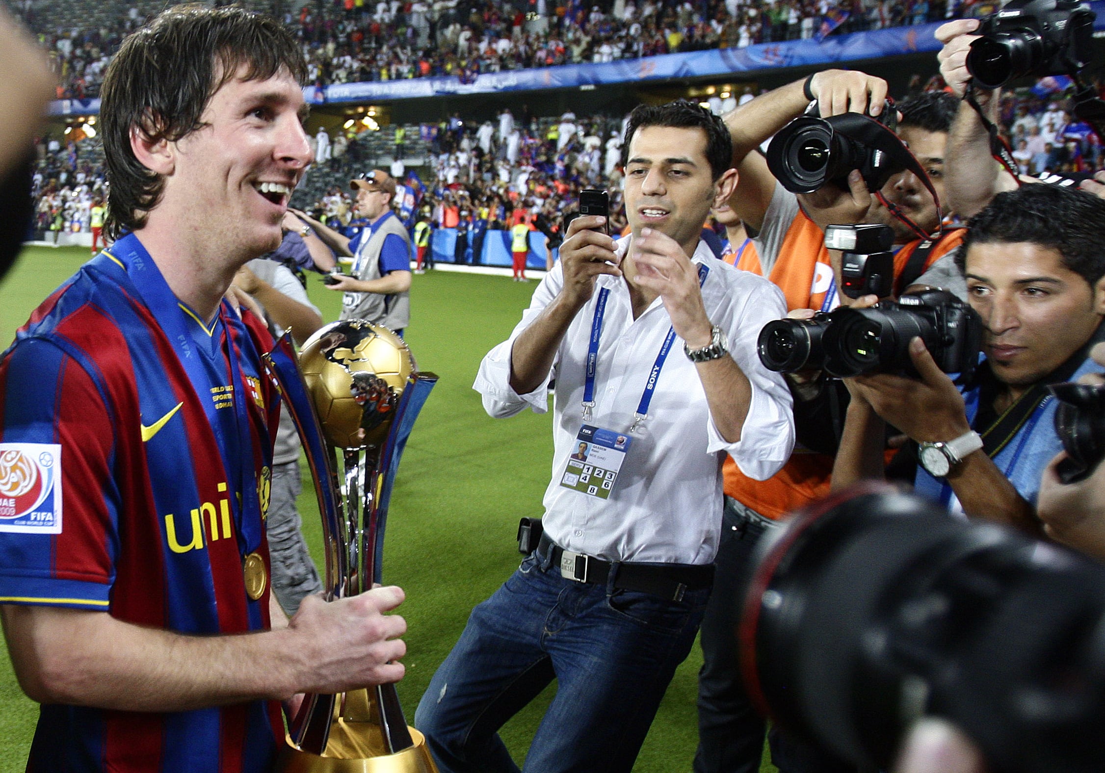 Rodeado de reporteros gráficos Messi celebra con el trofeo del Mundial de Clubes en el 2009 en la mano.