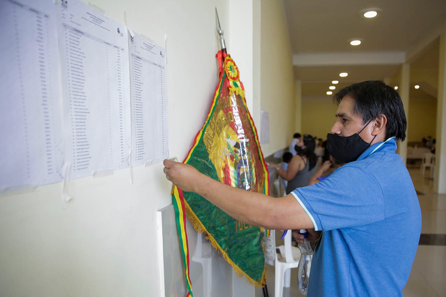 Tucumán; un funcionario del consulado de Bolivia cuelga un banderín de su país antes de comenzar la jornada electoral.