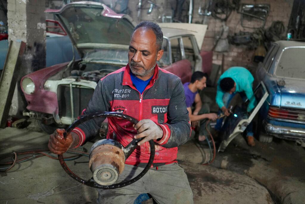 Mecánicos trabajan en el lote de un coleccionista de vehículos antiguos el viernes 8 de abril de 2022 en El Saff, gobernación de Giza, en las afueras de El Cairo. Mohamed Wahdan, un empresario egipcio y coleccionista de vehículos clásicos, dice haber acumulado más de 250 automóviles antiguos y clásicos en los últimos 20 años. (AP Foto/Amr Nabil)