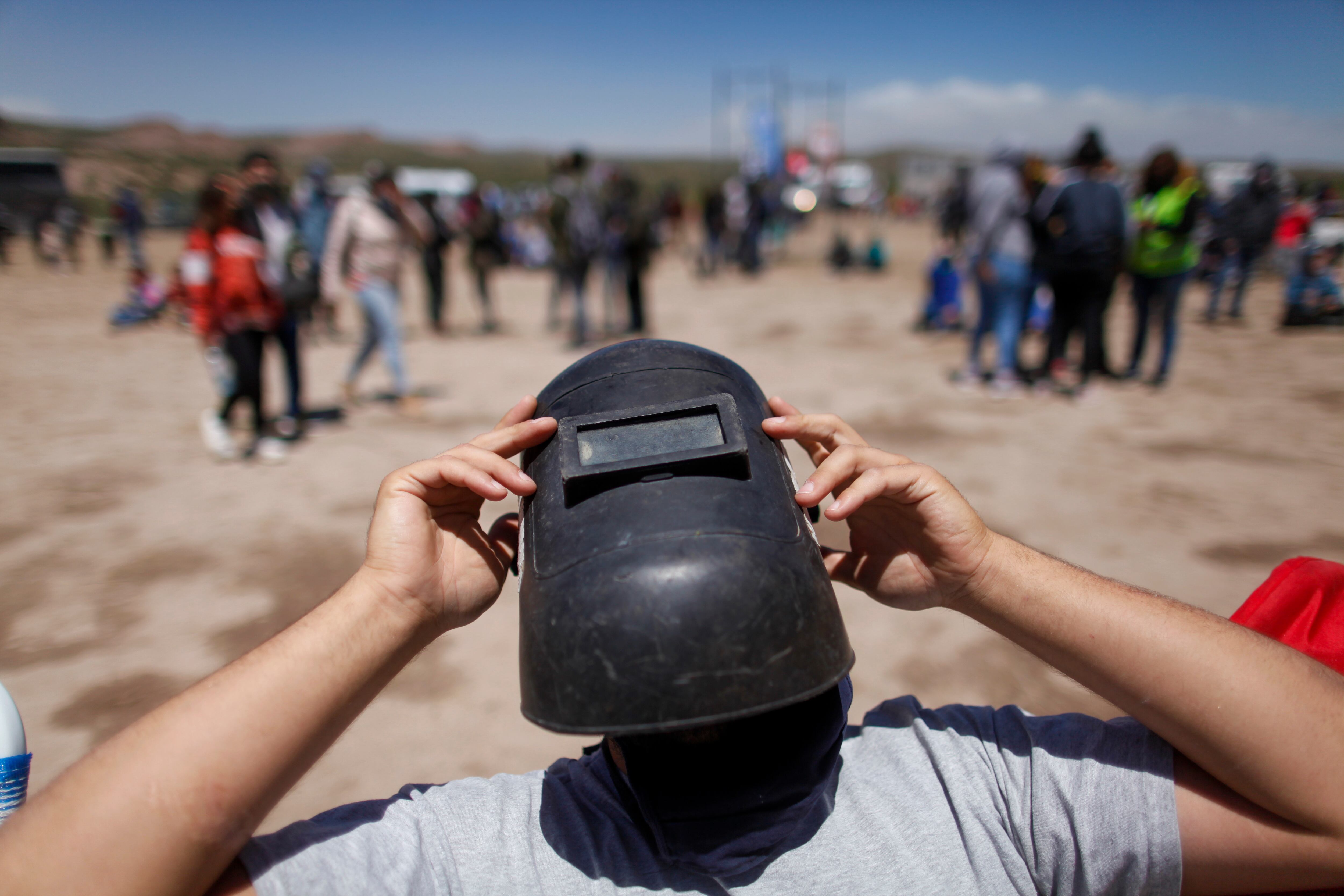 Usando una máscara de soldador como protección, un hombre ve un eclipse total en Piedra del Águila, Neuquén, Argentina.