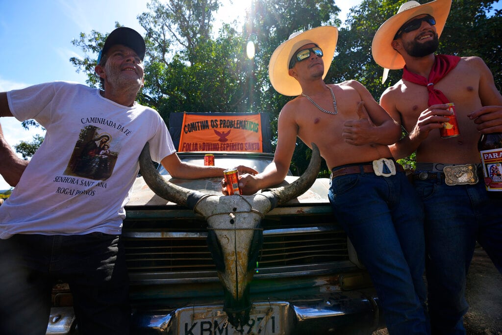 Unos hombres esperan para participar en las festividades por la tradición religiosa "Fiesta del Divino Espíritu Santo", en la región rural de Pirenópolis, en el estado de Goias, Brasil, el sábado 28 de mayo de 2022. (AP Foto/Eraldo Peres)