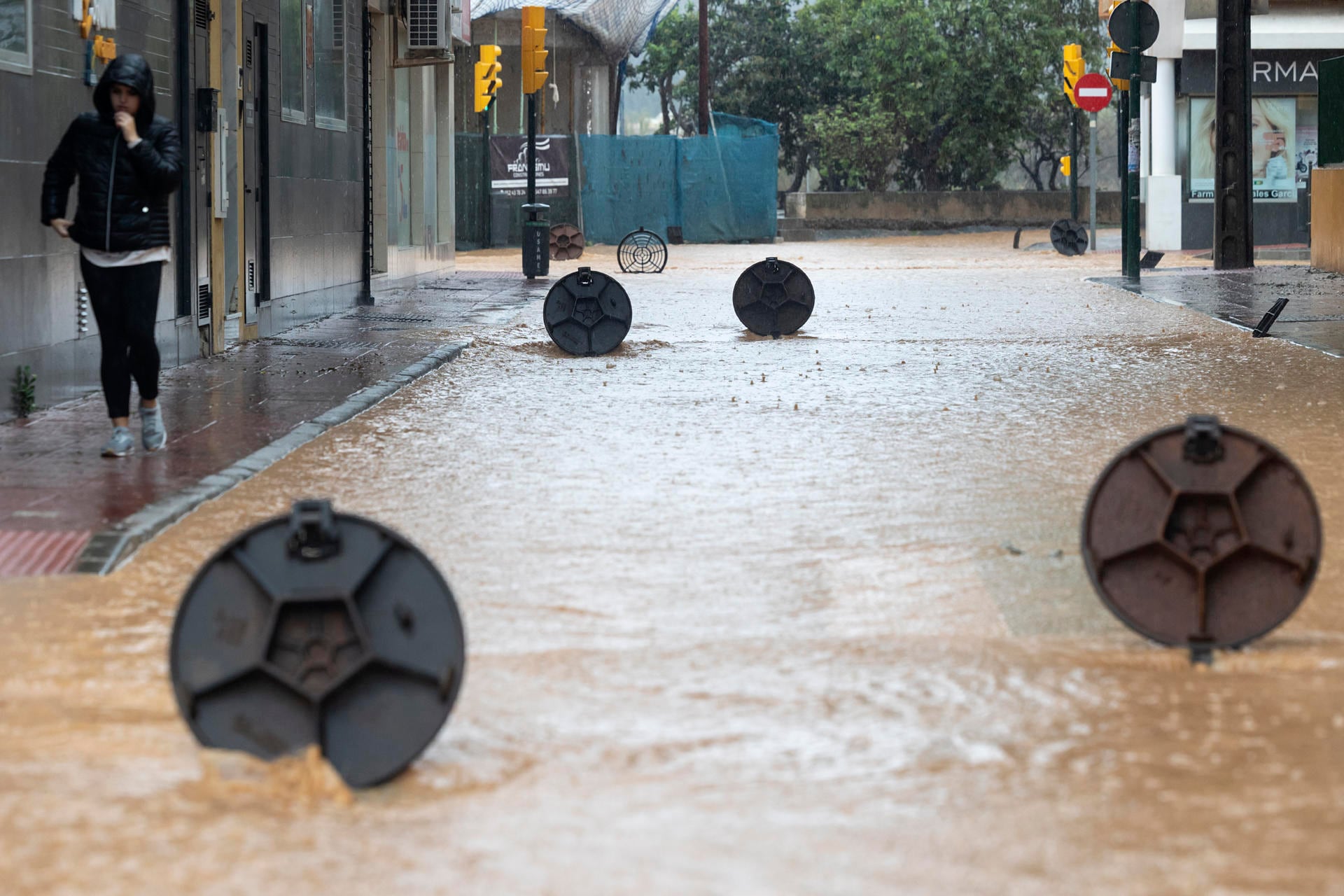 Cantarillas abiertas en una calle de la barriada de Campanillas en Málaga, en la que el paso de la DANA ha obligado a nuevos desalojos preventivos en el río Campanillas ante su posible desbordamiento. EFE/Daniel Pérez