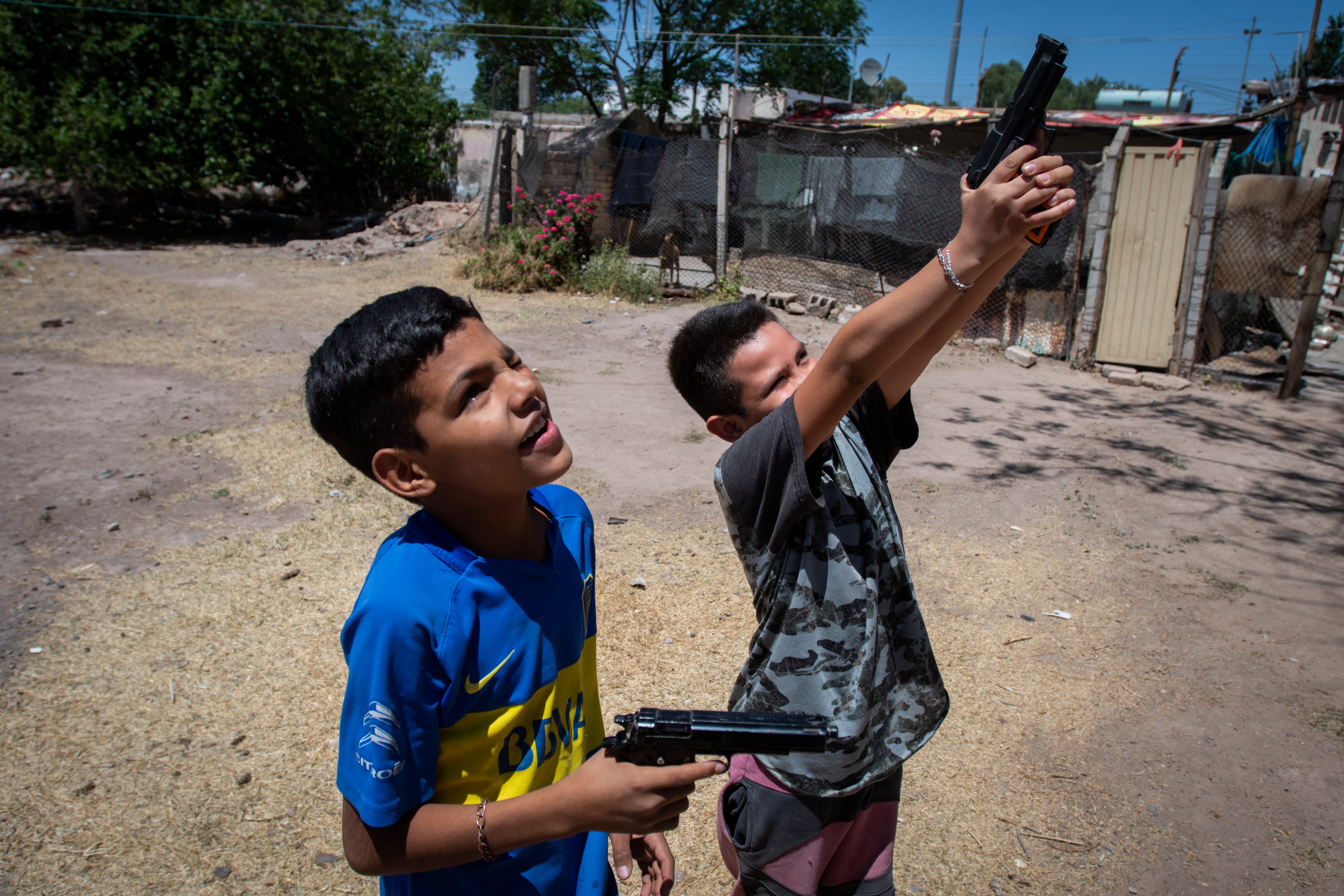 Kevin y Gonzalo, hijos de Daniela Paredes, se divierten jugando con pistolas de juguete. La madre de los chicos fue la única mujer que no firmó el plan de desarraigo en 2017, que entregaba 40.000 pesos y materiales de construcción a las familias para mudarse a otro lado. "No era una solución, íbamos a terminar volviendo", resume la mujer.