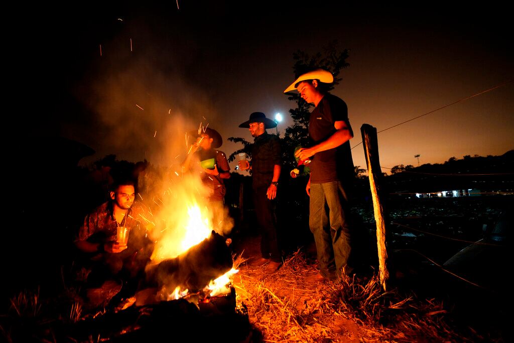 Varias personas se reúnen en una fogata durante las celebraciones por la tradición religiosa "Fiesta del Divino Espíritu Santo", en Pirenópolis, en el estado brasileño de Goias, el domingo 29 de mayo de 2022. (AP Foto/Eraldo Peres)